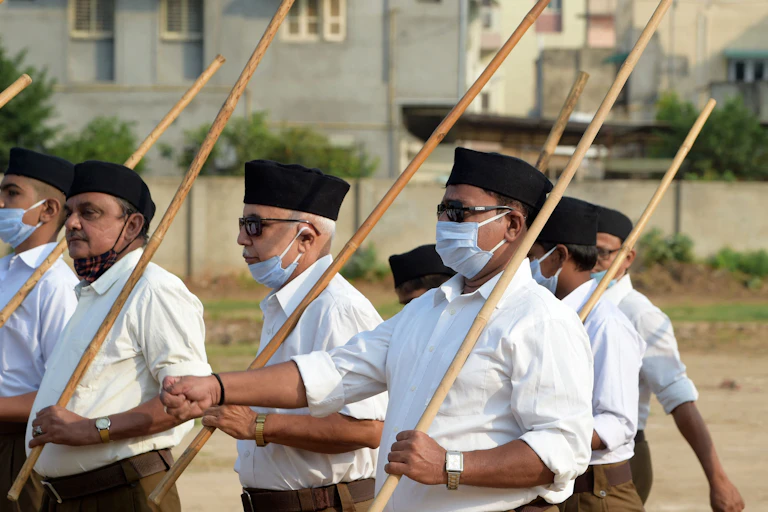 Five men, belonging to the Hindu nationalist group Rashtriya Swayamsevak Sangh, holding sticks and marching.