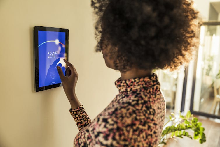 woman adjusting digital wall thermostat