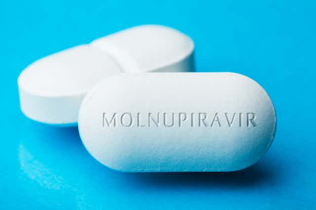 A photograph of two large, white pills, one with MOLNUPIRAVIR printed on the front.