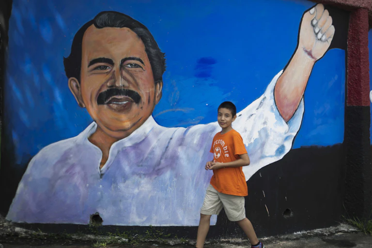 Young boy walks past mural depicting Nicaraguan leader Daniel Ortega.