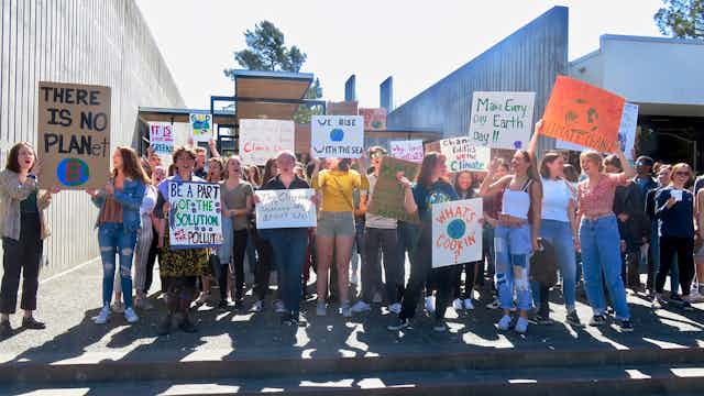 A group of young people hold climate-related signs