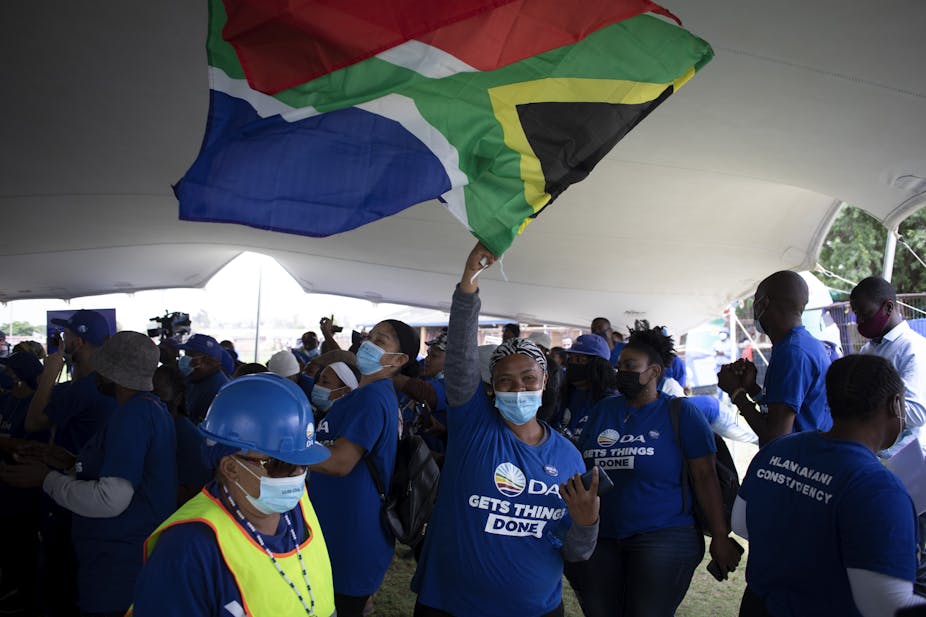 A woman wearing a COVID-19 mask and Democratic Allliance regalia waves the South African flag at a party election campaign meeting 