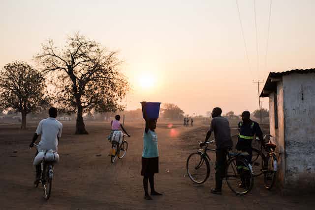 People bike and carry water in a dry village in Malawi during a drought.