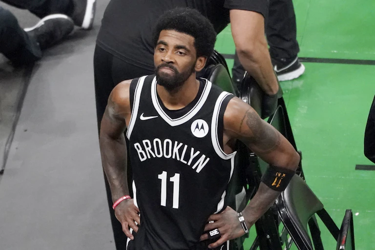 Kyrie Irving, wearing his Brooklyn Net jersey with number 11 written on it, rests his hands on his was it looks up at the fans at TD Garden after they defeated the Boston Celtics