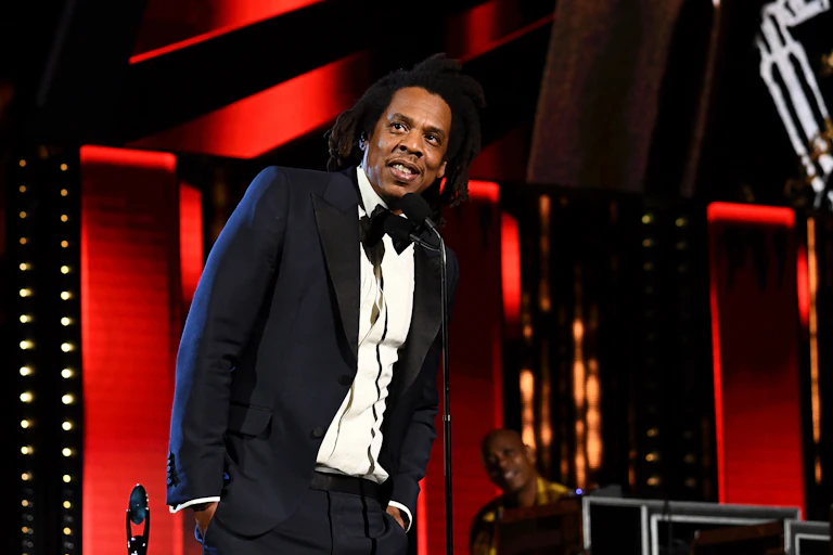 A formally dressed Black man gives a speech on stage.