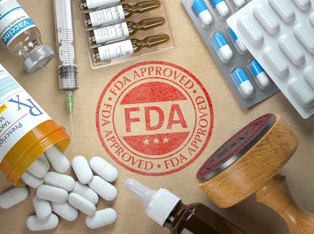 The FDA "stamp of approval" surrounded by prescription pills and other medication