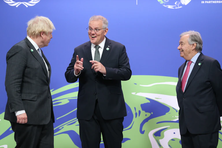 three men in suits stand on stage