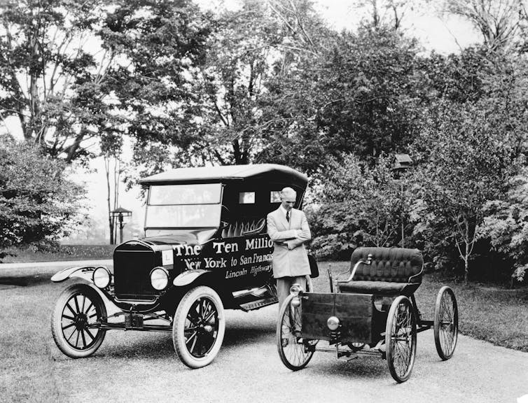 man stands between two vintage cars