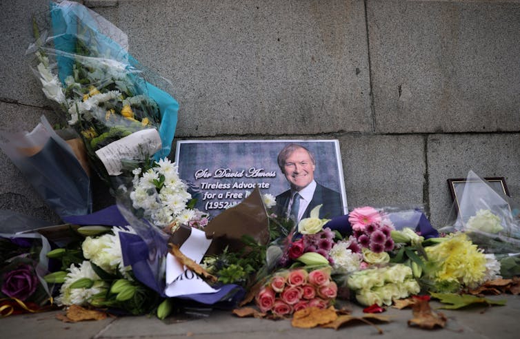 A photo of David Amess surrounded by flowers left in his memory.