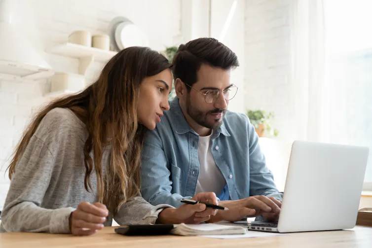 A middle aged couple do financial planning together on a laptop.
