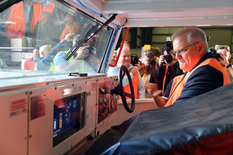 man in orangne vest looks at steering wheel