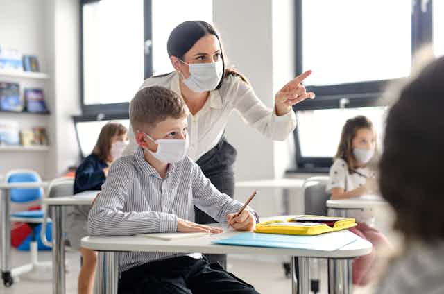 Teaching and student in classroom with masks on.