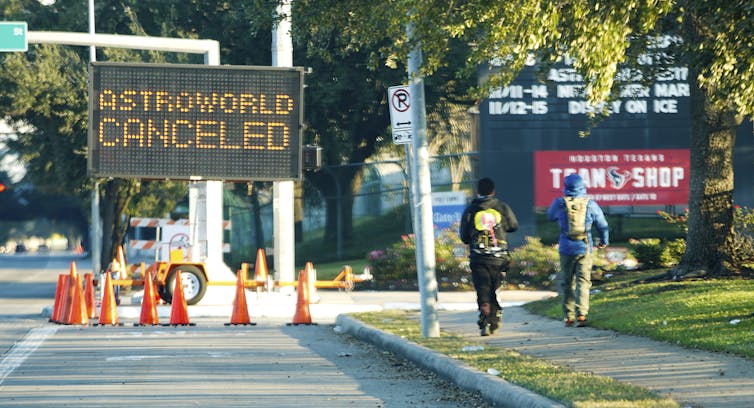 People walk past a sign announcing Astroworld is canceled outside NRG in Houston.