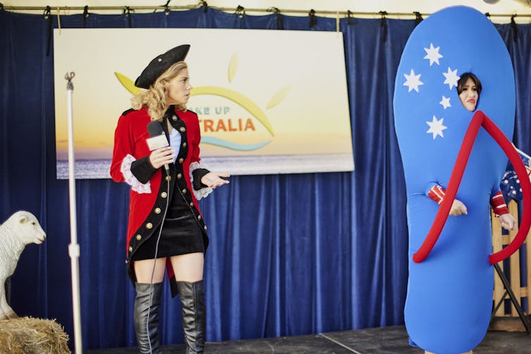 A white woman dressed like a coloniser, and an Aboriginal woman dressed as an Aussie flag thong.