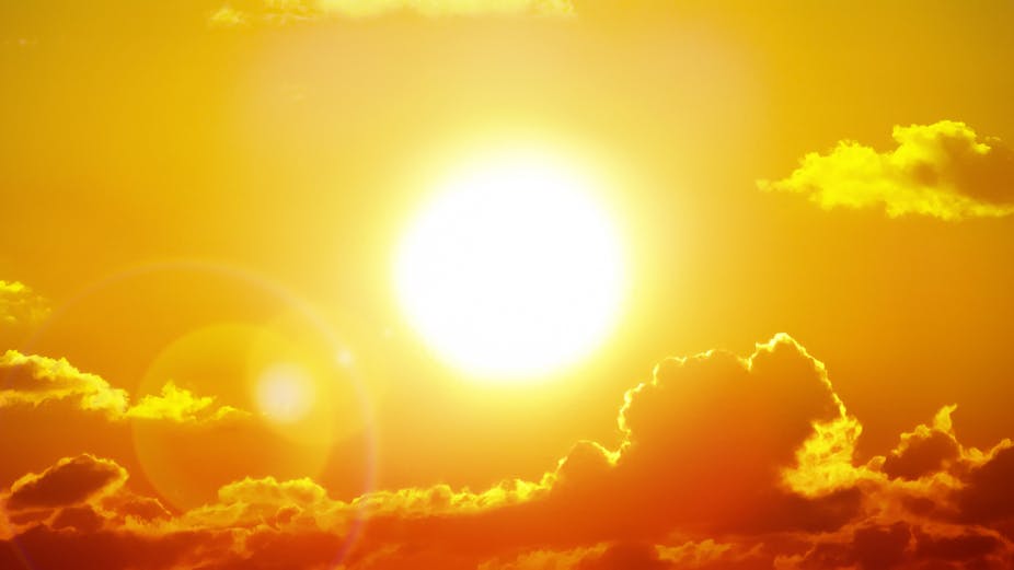 The sun is pictured burning brightly in the sky, with a few clouds above it and a long bank of clouds beneath it. The whole image is tinted yellow.