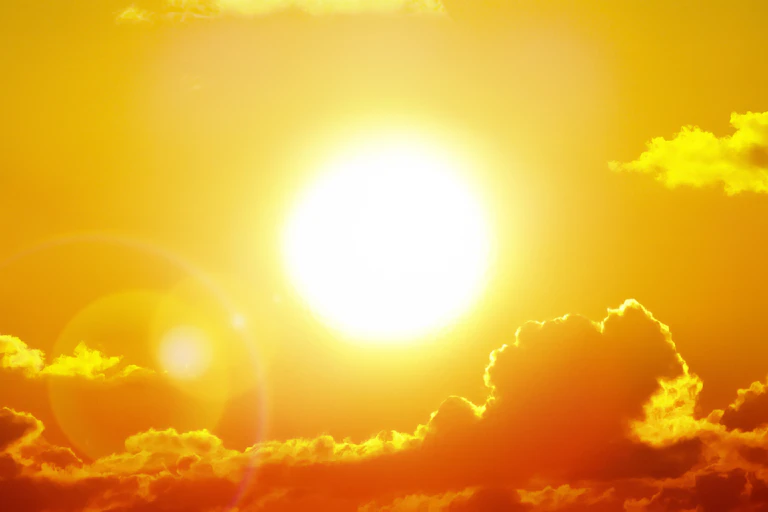 The sun is pictured burning brightly in the sky, with a few clouds above it and a long bank of clouds beneath it. The whole image is tinted yellow.