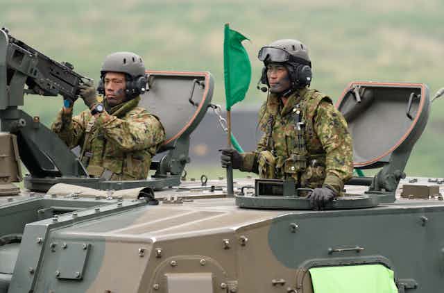 Two members of Japan's self-defense forces manning an armoured personnel carrier during live fire exercises in May 2021.