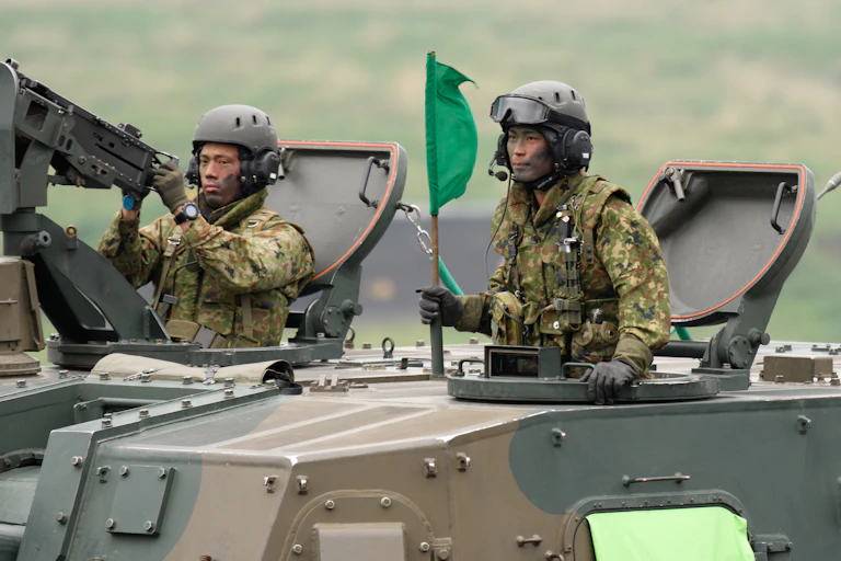 Two members of Japan's self-defense forces manning an armoured personnel carrier during live fire exercises in May 2021.