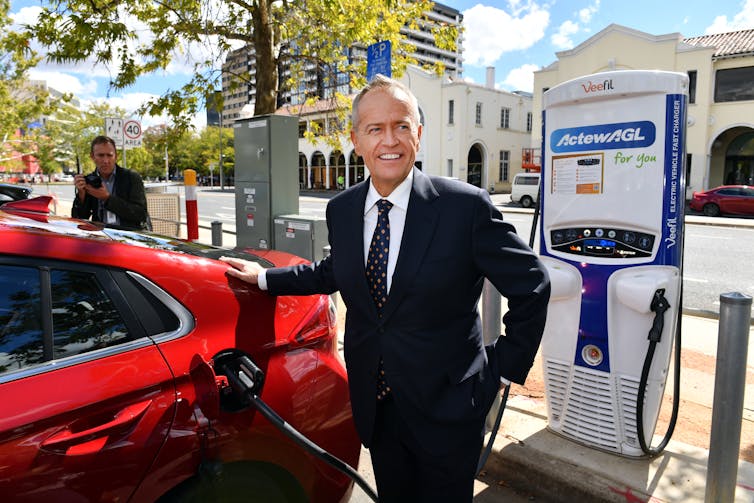 man recharges electric car