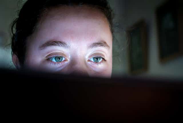 A young girl stares at her laptop screen.