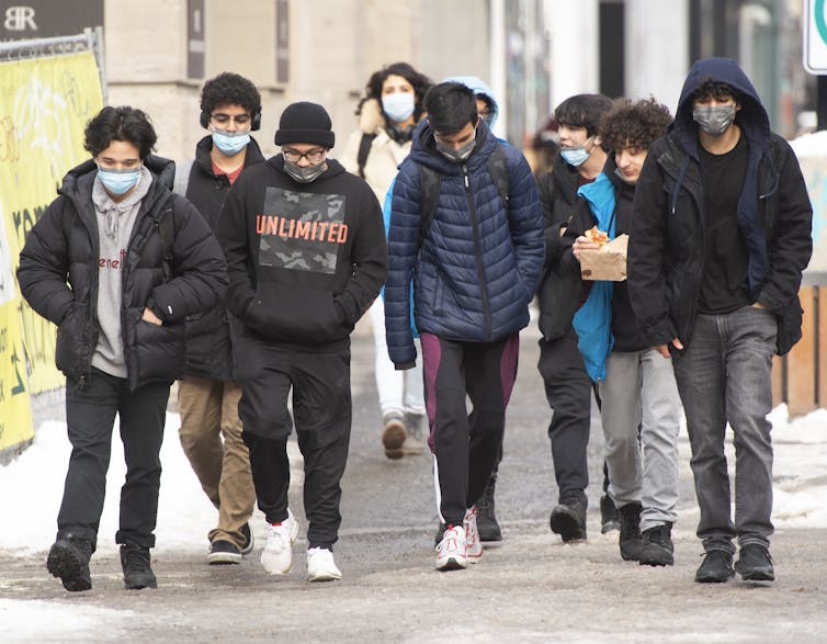 A group of young people is seen walking down the street.
