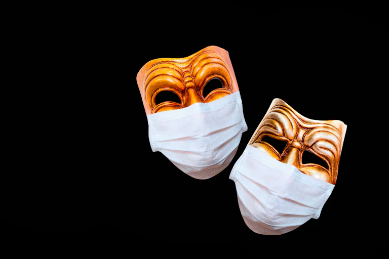 Two traditional drama commedia del'Arte masks covered in face masks.