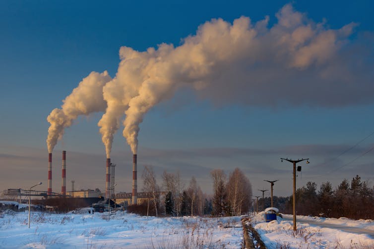 Winter sunset in the industrial zone of the city of Myski, in the South Of Western Siberia, Kuzbass region in Russia. Smoke and steam comes out of industrial chimneys.