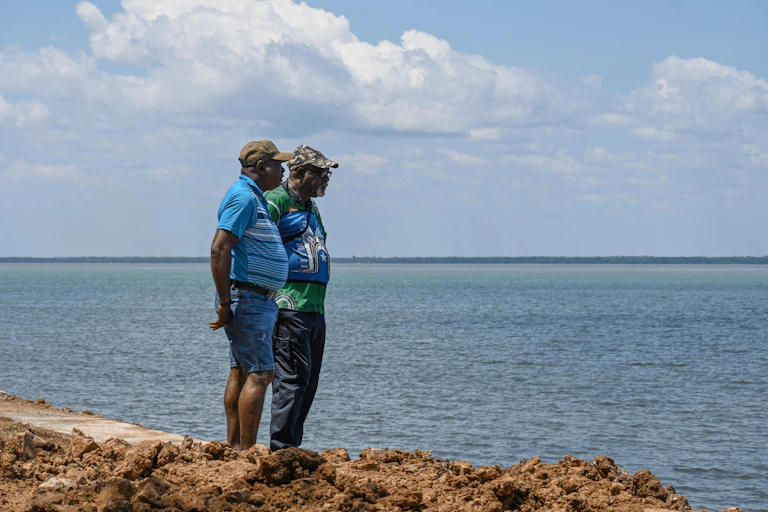 Two people standing by the ocean looking out.