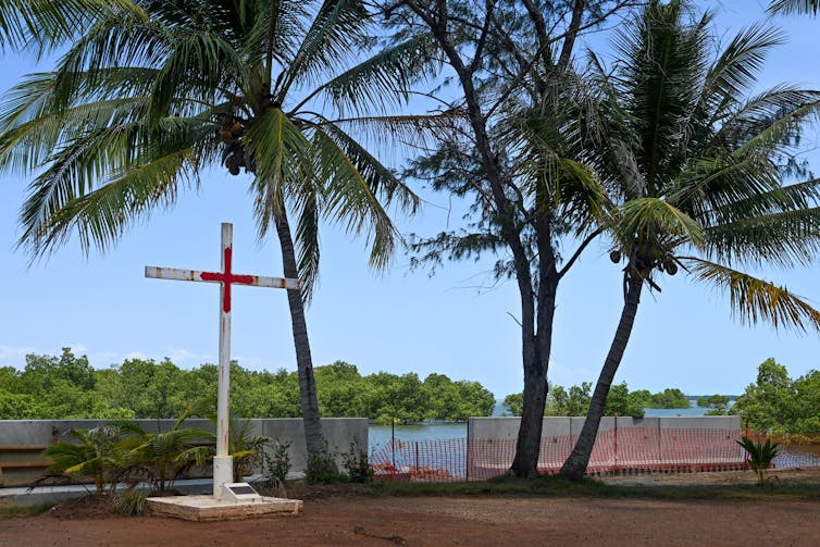 A cross in front of ocean.
