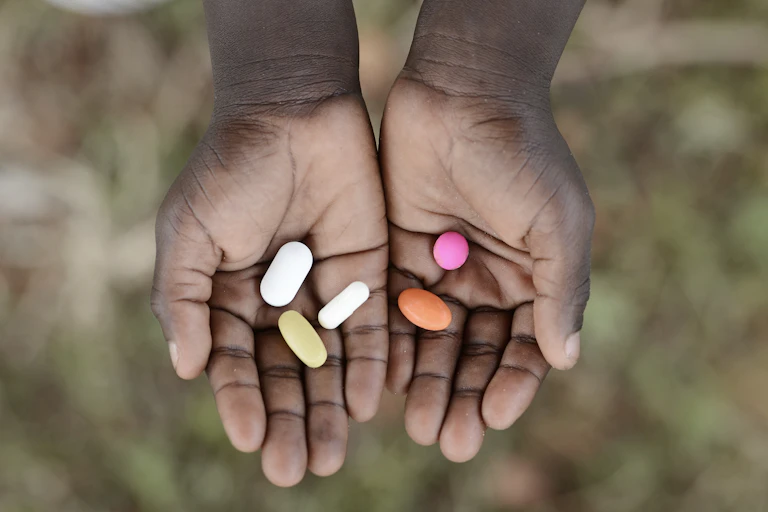 African child holding pills in hands