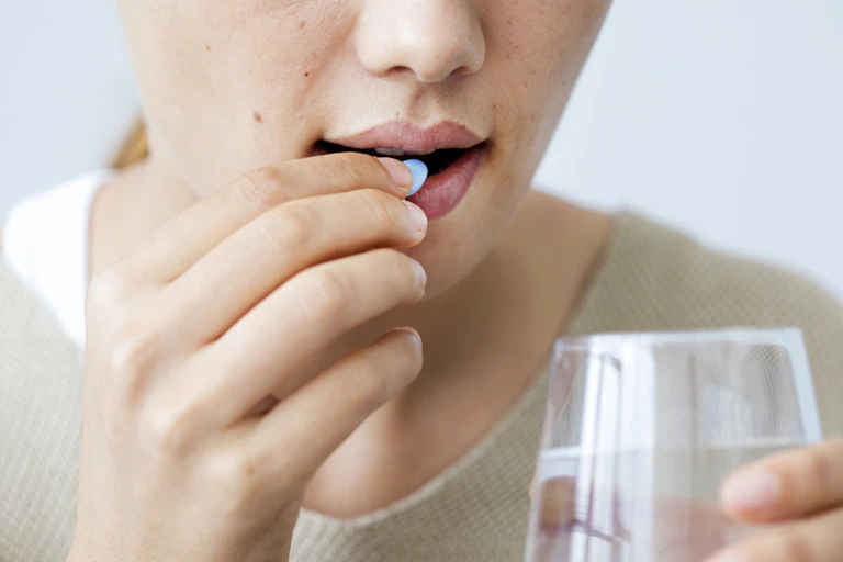 A woman taking a pill with water