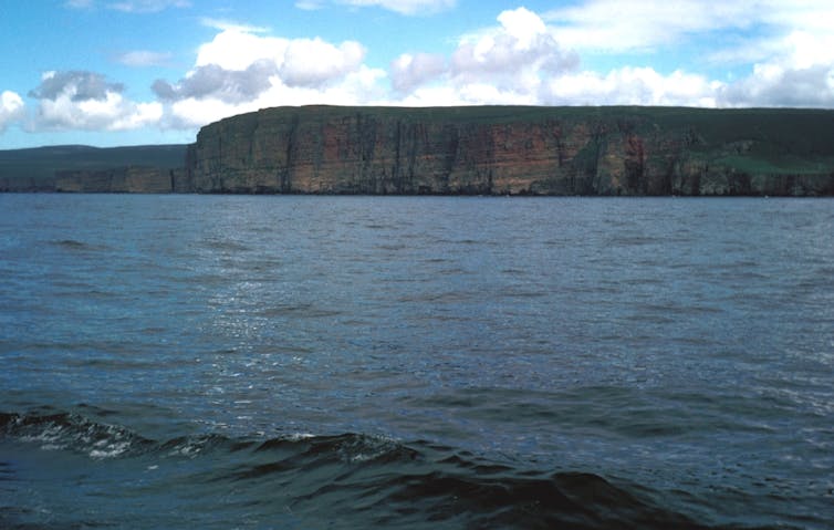 A headland on the horizon with choppy water in the foreground.