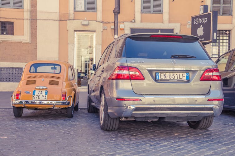 A small old car beside a large new car