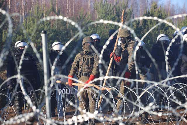 Polish security forces standing guard at the barbed wire border with Belarus.