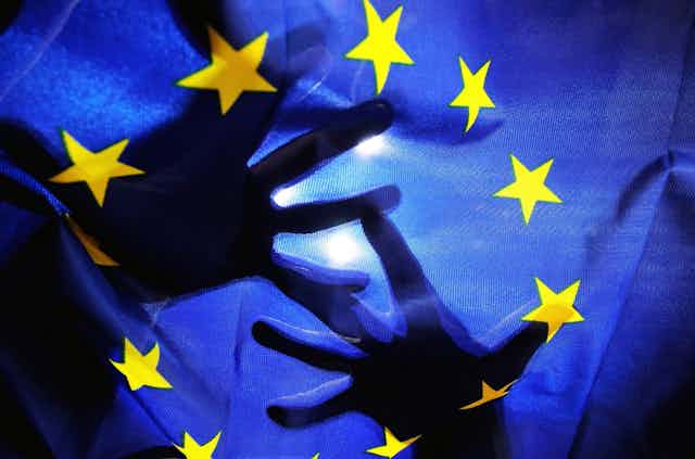 Drapeau européen avec des silhouettes de mains en transparence derrière