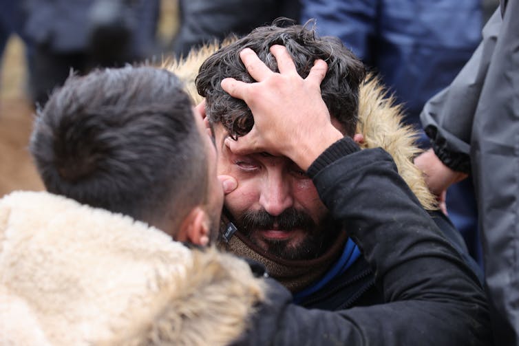 A man examines another man's left eye at the border between Belarus and Poland.