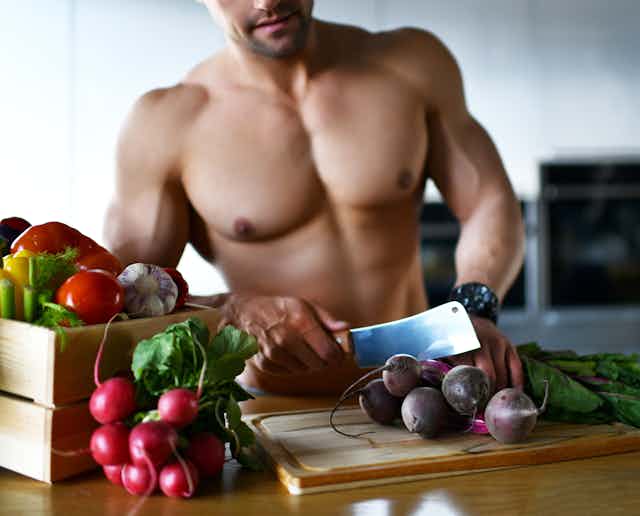 topless man cuts vegetables