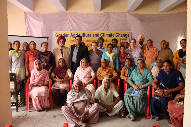 People sit and stand against a backdrop reading 'Gender, Agriculture and Climate Change'