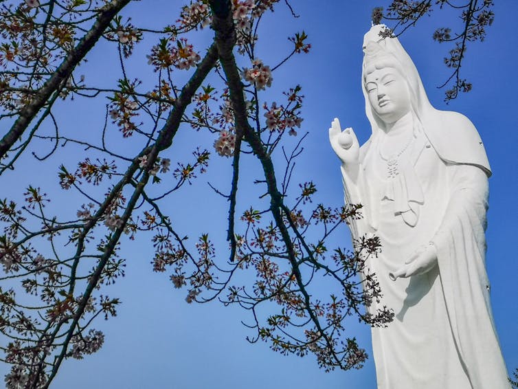 Una estatua del bodhisattva Guanyin, que se representa como una mujer de cabello largo y suelto vestida con túnicas blancas,