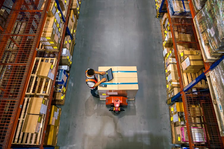 Looking down on a worker at a computer in a large warehouse