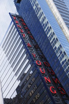 Ernst & Young is spelled out vertically in red neon lights on the side of a building.