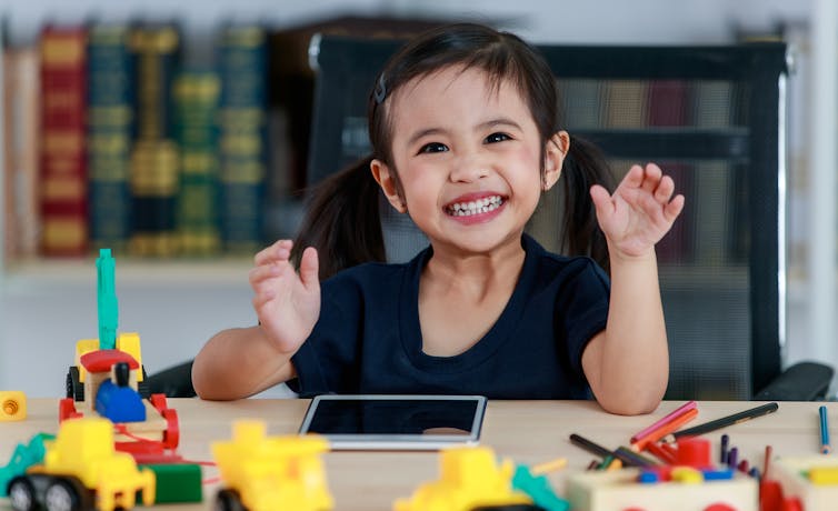 Young child with toys and a digital device