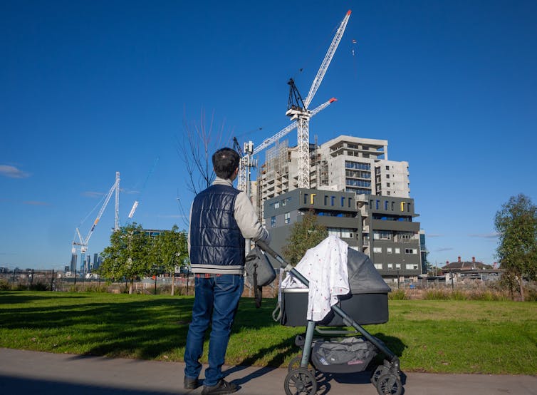 A man with a pram looks at a construction site.