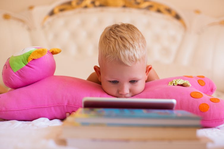 Young child watching or listening on a digital device.