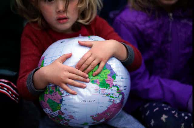 child's hands hold inflatable globe