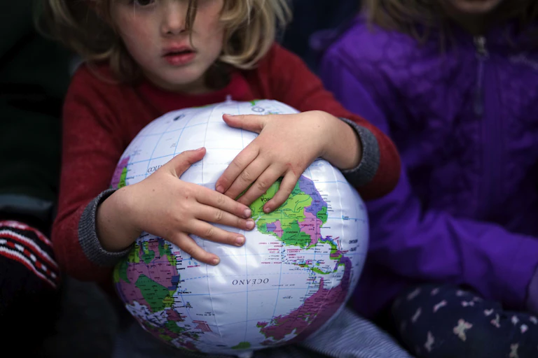child's hands hold inflatable globe