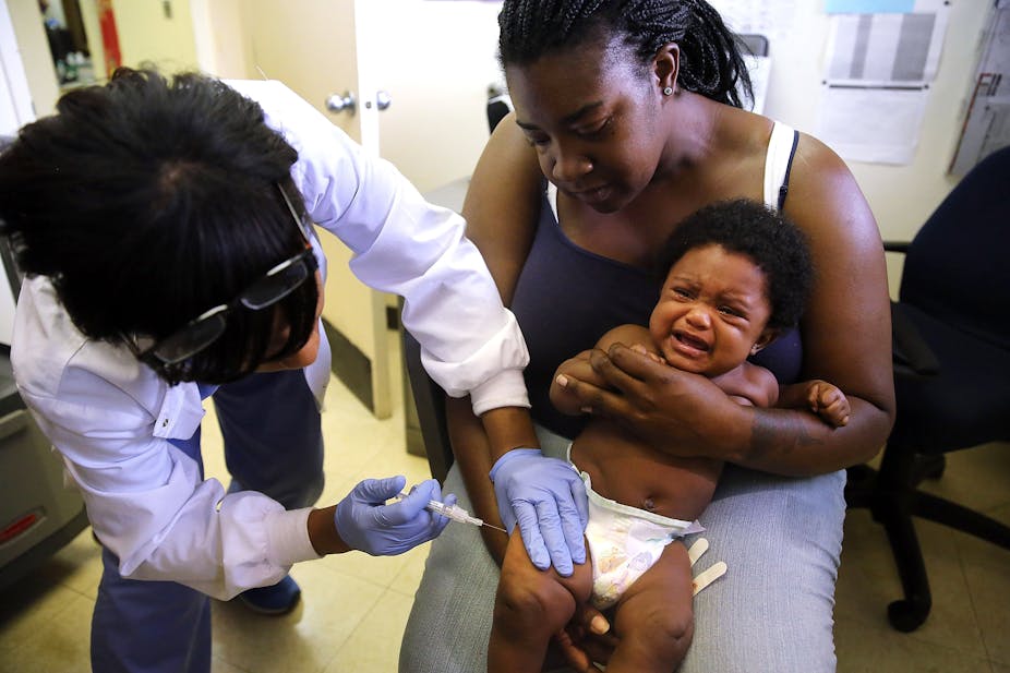 woman holds crying baby getting an injection