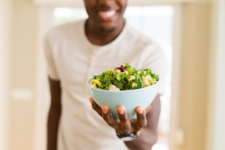 Man holds large salad bowl.
