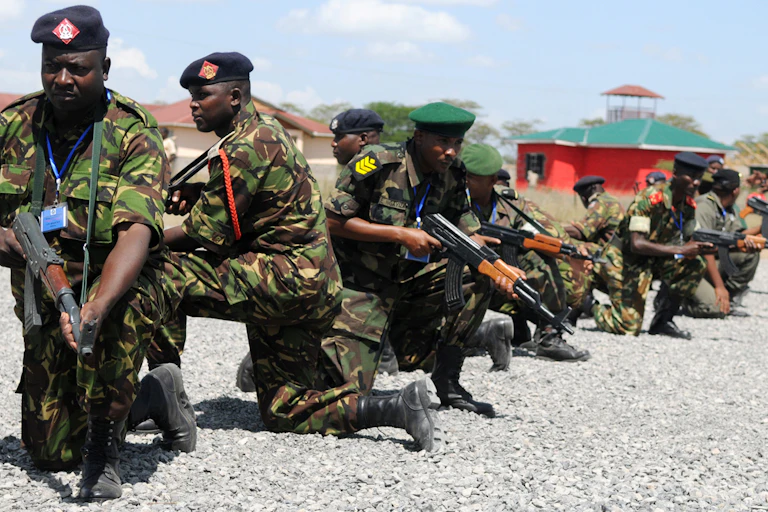 Men with guns kneeling down in an open area