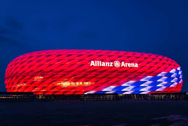 An image of Bayern Munich's Allianz stadium lit up in red at night.